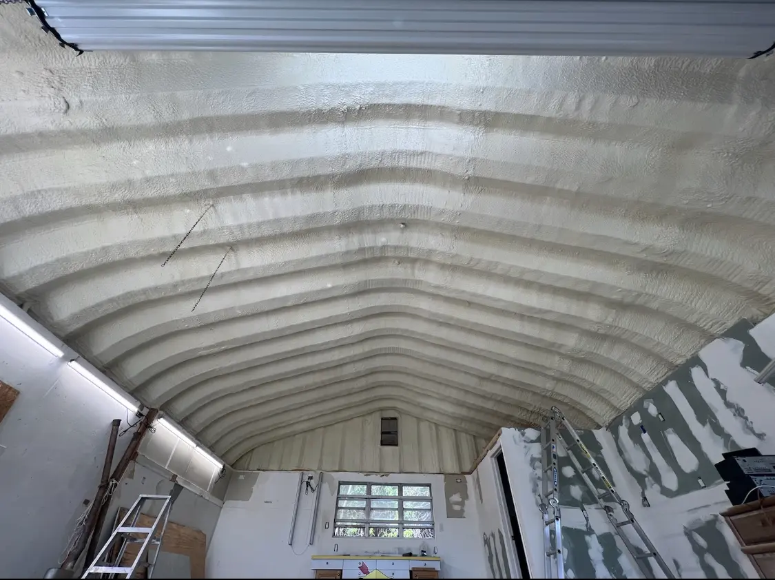 Spray polyurethane foam applied to the underside of a metal roof deck in Riga